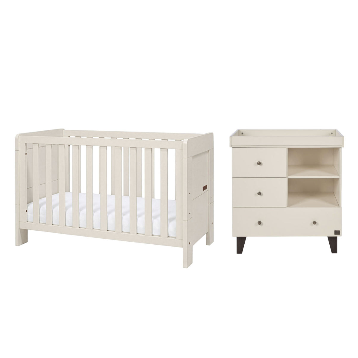 A white convertible cot bed and matching three-drawer nursery dresser with open shelves and a removable baby-changing unit, shown side by side on a plain white background.