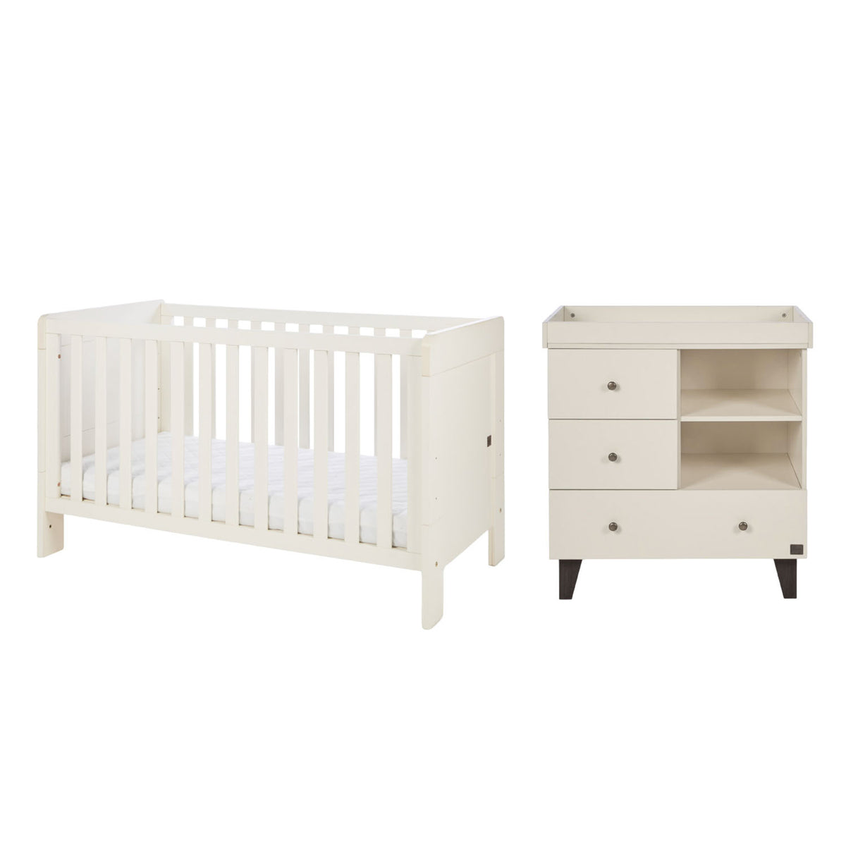 A white convertible cot bed and matching three-drawer changing table with open shelves, shown on a plain white background.