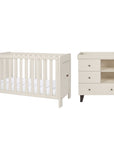 A white convertible cot bed and matching three-drawer nursery dresser with open shelves and a removable baby-changing unit, shown side by side on a plain white background.