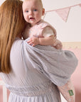 Mother holding baby dressed in the Tiny Tails sleep bag, featuring a soft pink woodland print for cosy comfort and style