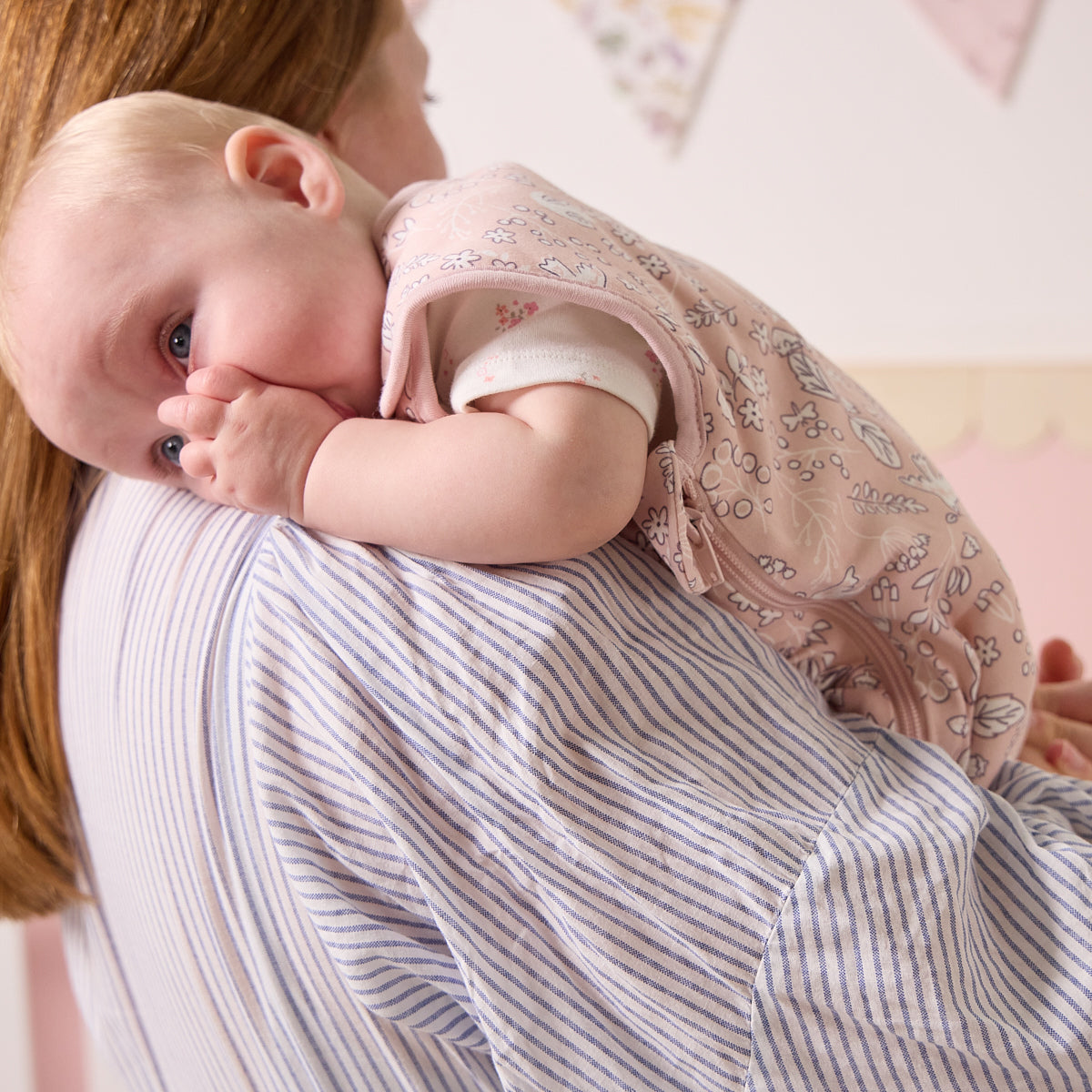 Baby resting on parent’s shoulder in the Tiny Tails sleep bag, gently sucking thumb in a calm and comforting bedtime moment
