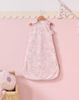 Tiny Tails baby sleep bag hanging on pink wall with bunting, styled with matching mushroom cushion and woven basket detail