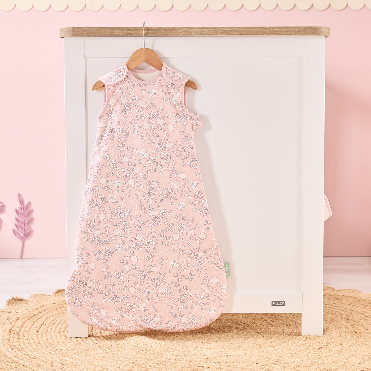 Tiny Tails baby sleep bag hanging in soft pink nursery, featuring calming woodland print for a serene and stylish bedtime look