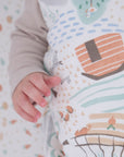 Close-up of baby’s hand resting on the Good Life sleep bag, highlighting the soft fabric and playful farmyard pattern details