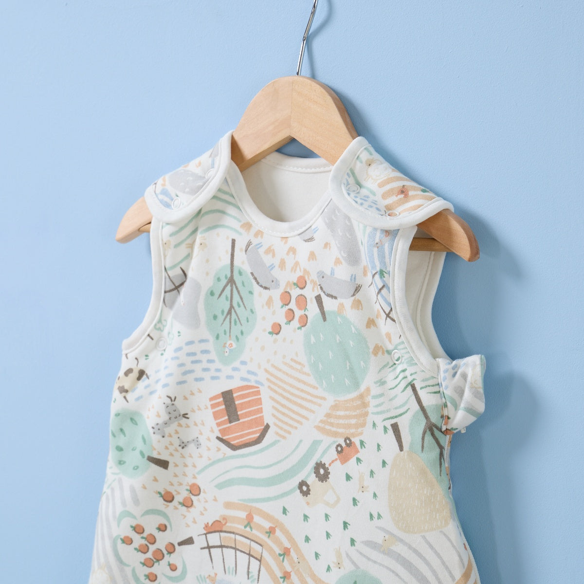 Hanging close-up of Good Life baby sleep bag with shoulder poppers and playful countryside print in soft neutral tones.