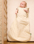 Baby lying in the Love Cats baby sleep bag in a wooden cot bed