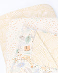 Cutout view of the Good Life bedside crib starter pack with two patterned fitted sheets and a reversible coverlet featuring playful farmyard motifs