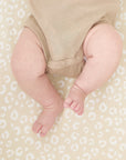 Close-up of baby’s legs resting on the Love Cats fitted sheet in soft beige with playful cat-inspired spots and gentle texture