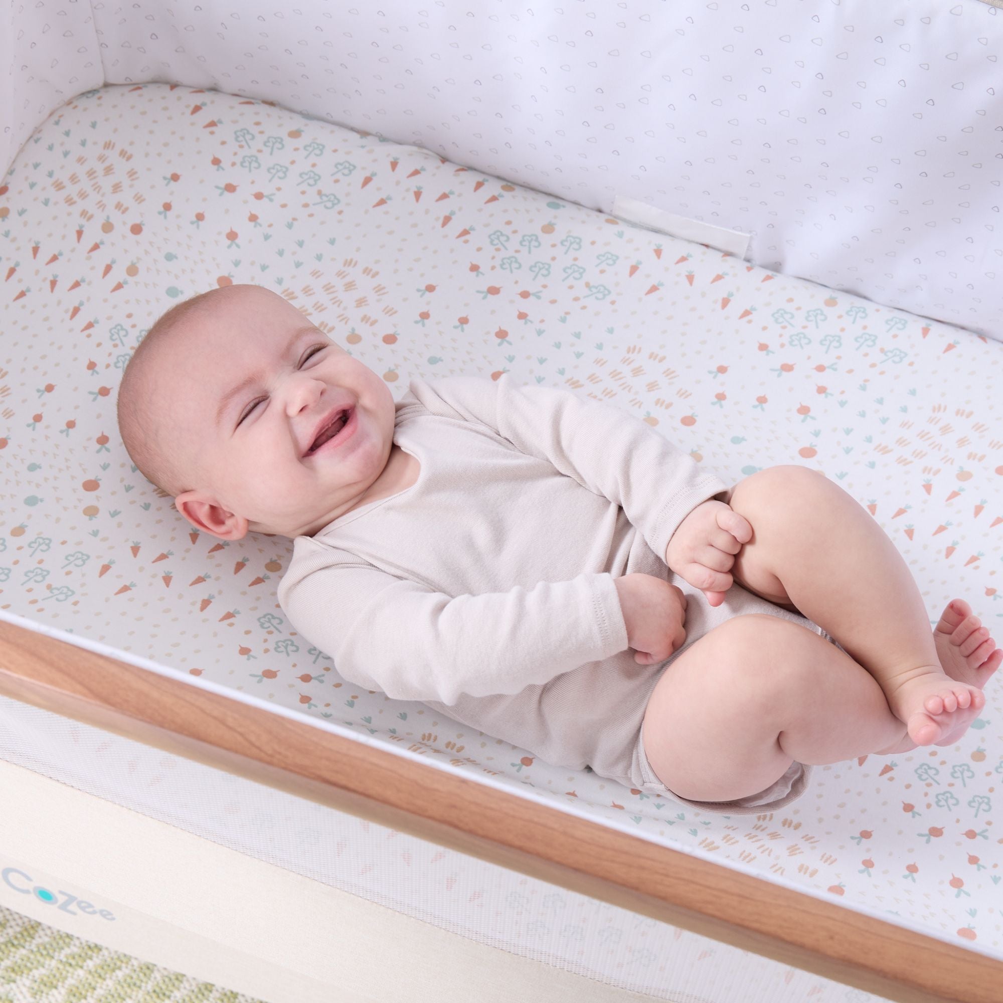 Baby lying in the CoZee next to me crib with the Good Life fitted sheet