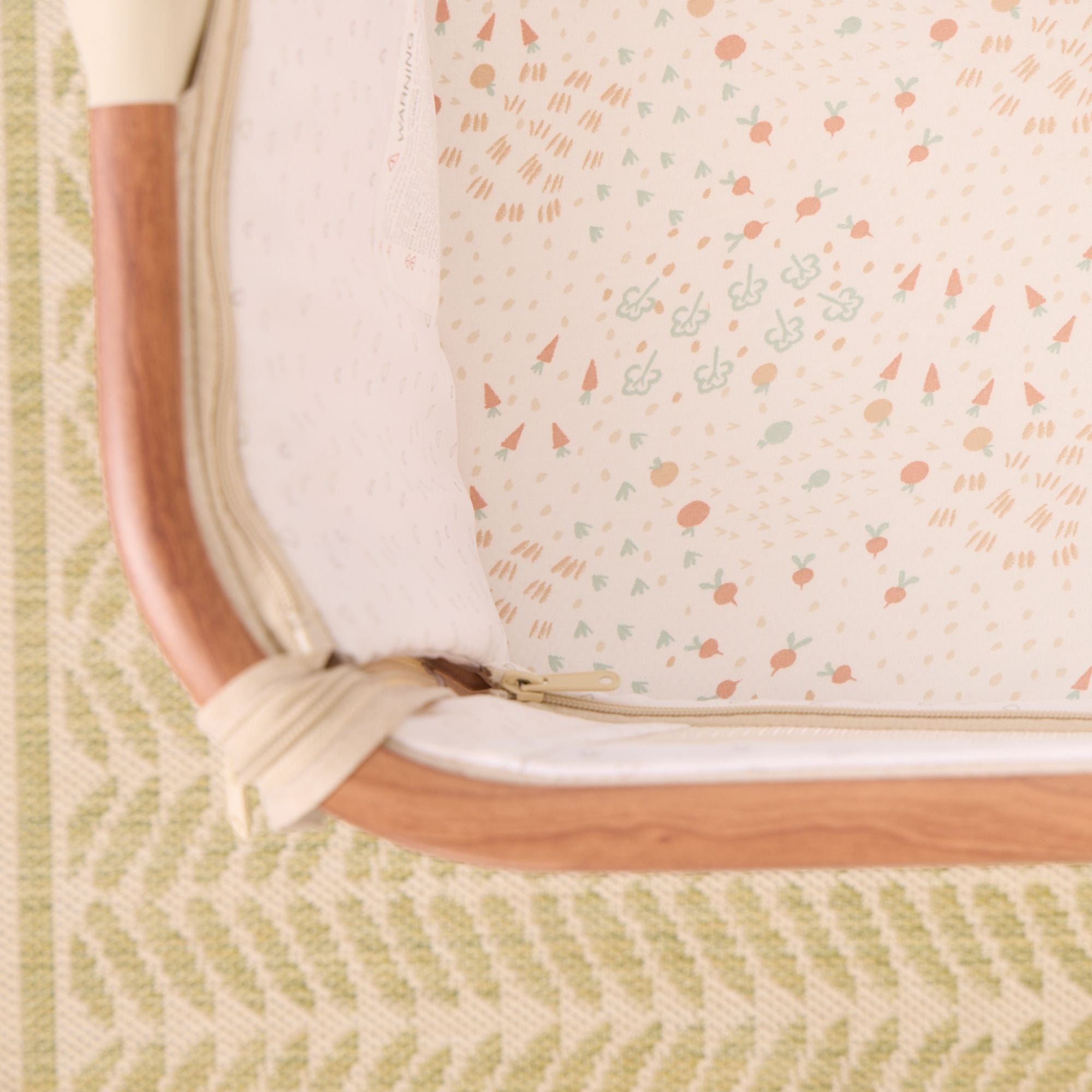 Close-up of the CoZee bedside crib with the Good Life bedside crib fitted sheets featuring small illustrations.