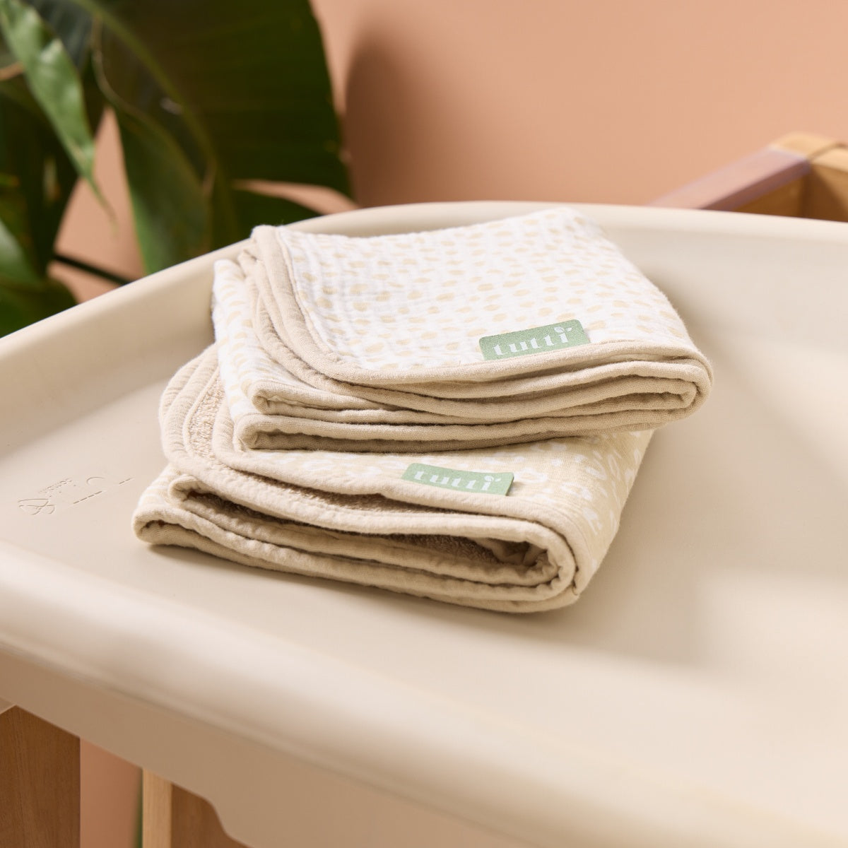 Folded stack of beige and cream muslin changing mat liners with Tutti Bambini labels, showing soft layers and natural texture
