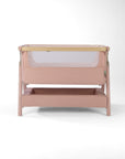Front cutout view of the CoZee Air 2 bedside crib in blush, showing breathable mesh panel, wooden trim and integrated storage shelf.