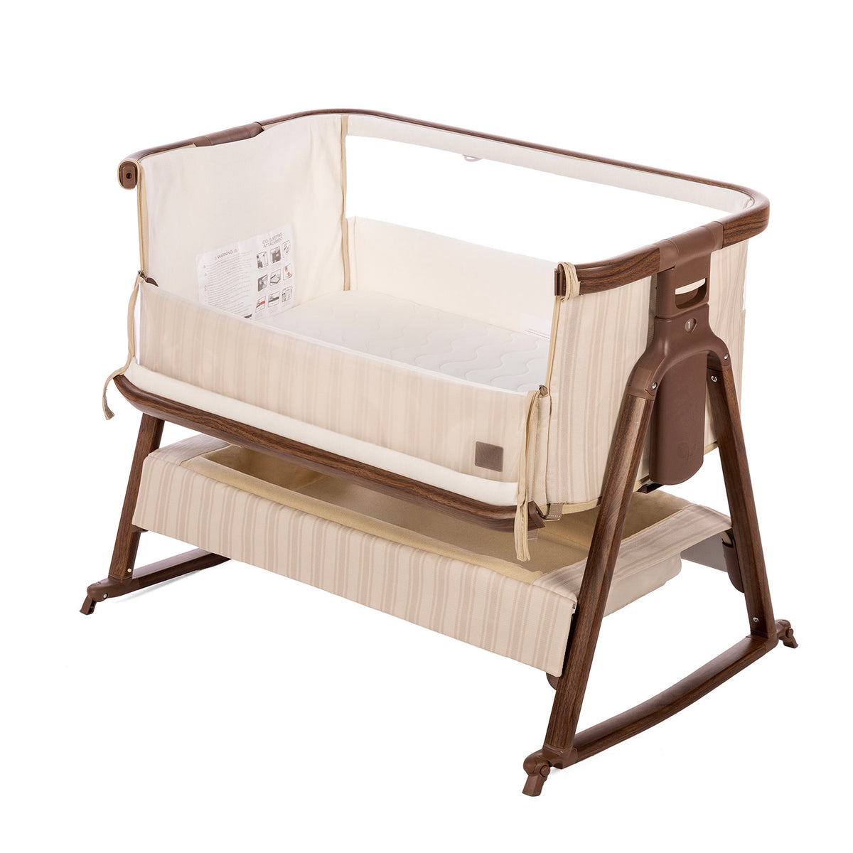 A baby bedside crib with a cream-colored striped fabric body and a dark brown wooden frame, shown on a white background.