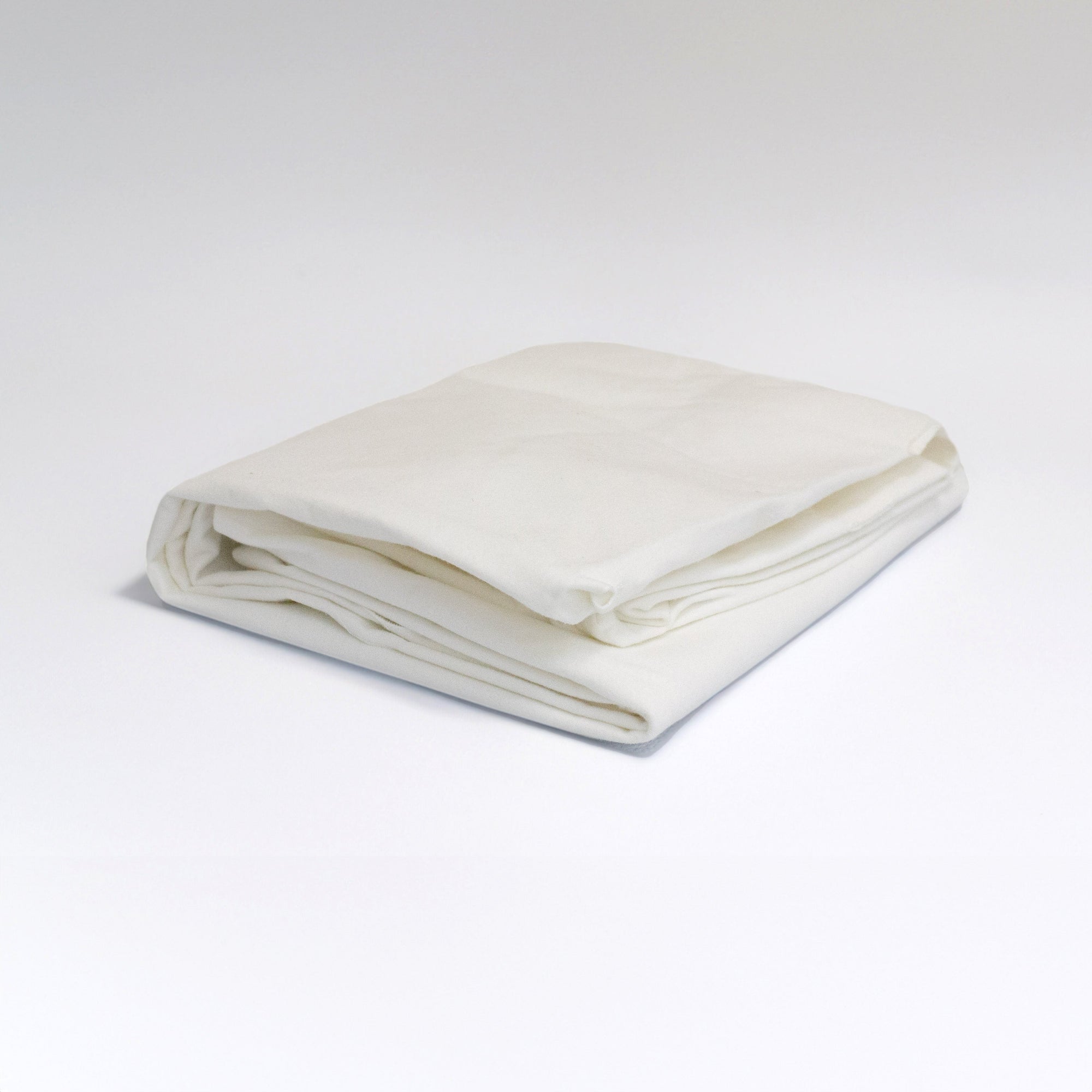 Folded white CoZee Go fitted sheet on a light background