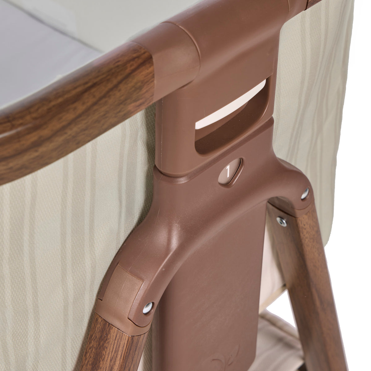 Angle view of the CoZee Air bedside crib in rich walnut and cashmere vintage stripe showing numbered height adjustment settings for bedside alignment.
