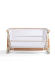 Front cutout of the CoZee Scandi bassinet with lowered side panel, showcasing mesh sides and wooden frame