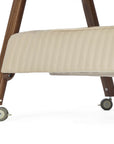 Close-up of a mobile bedside crib frame with a  quilted cashmere fabric, dark walnut wooden legs, and gray caster wheels on a white background.