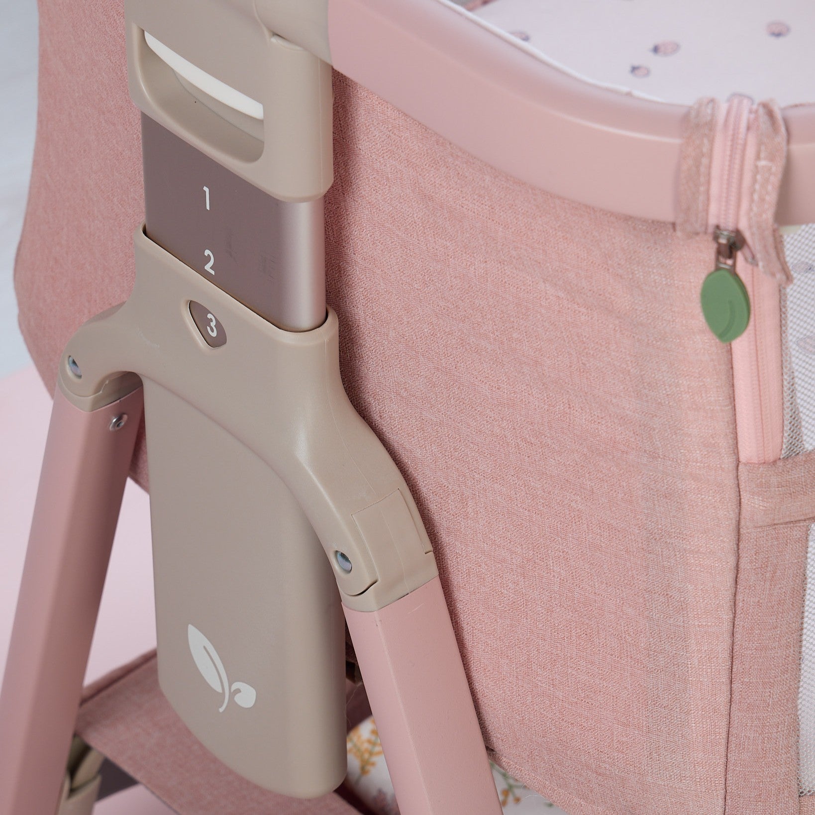 Close-up of CoZee Zen pink crib with adjustable height settings on a light background