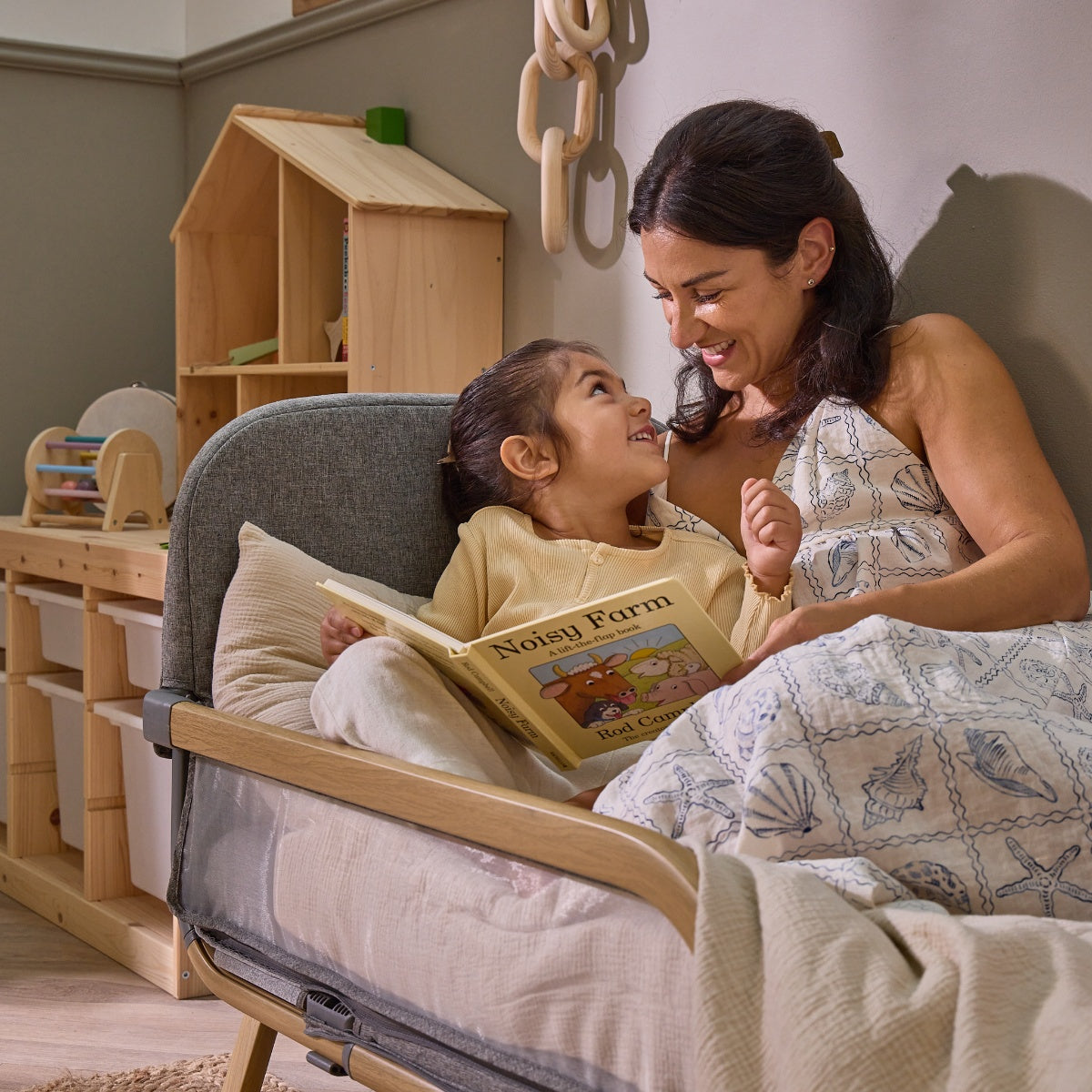 Mum and toddler share a book together on the CoZee XL in oak and charcoal, styled as a toddler bed for bonding moments