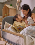 Mum and toddler share a book together on the CoZee XL in oak and charcoal, styled as a toddler bed for bonding moments