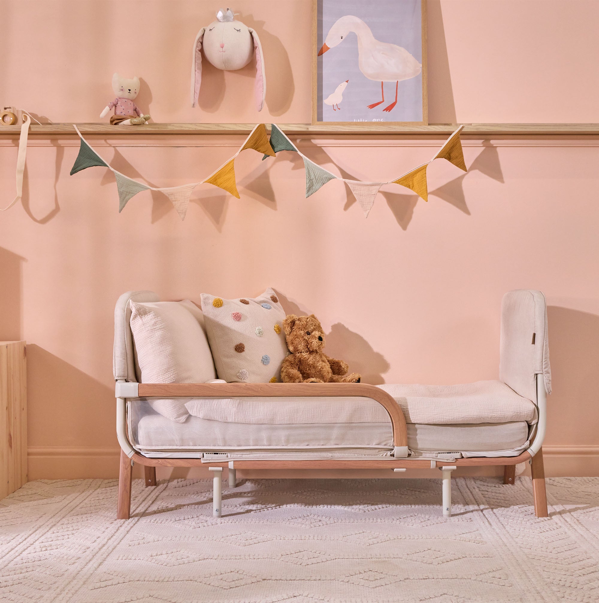 Lifestyle view of the CoZee XL Scandi in junior bed mode styled with soft bedding and toys, designed to ease transition from cot to toddler bed.