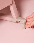 Close-up of the CoZee Air 2 bedside crib brake being engaged by hand, showing the locking castor for added stability and safety.