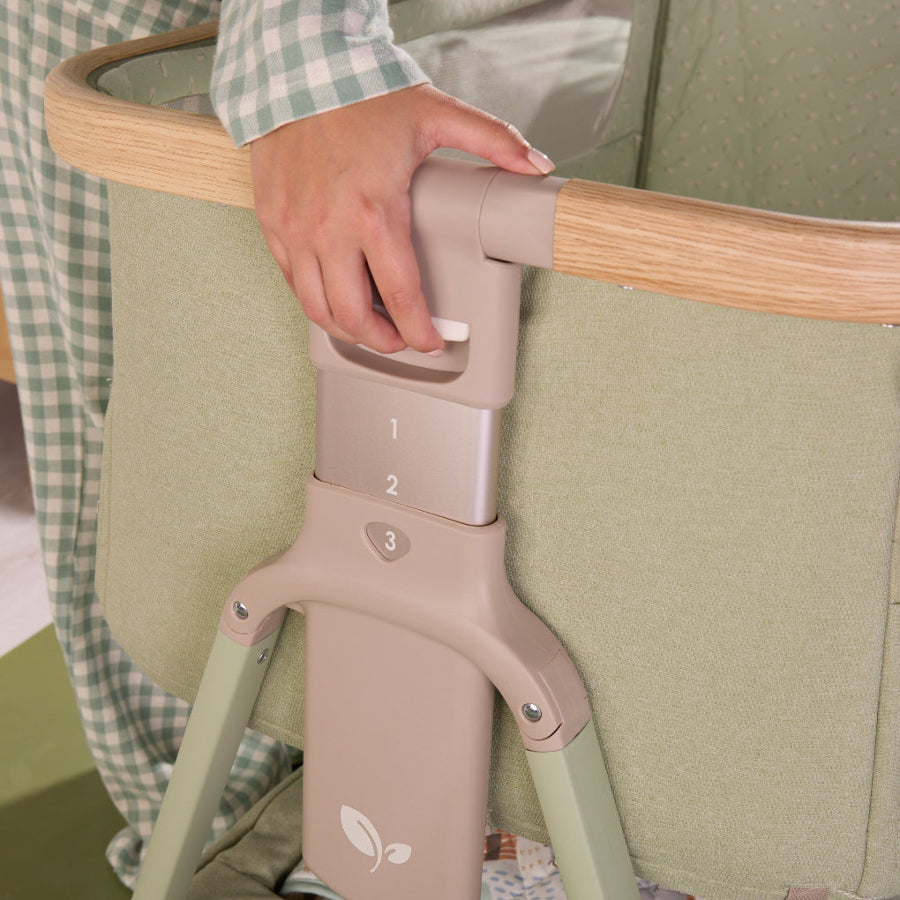 Detail of the CoZee Air 2 bedside crib in eucalyptus showing height-adjustable leg mechanism with numbered settings for precise positioning.