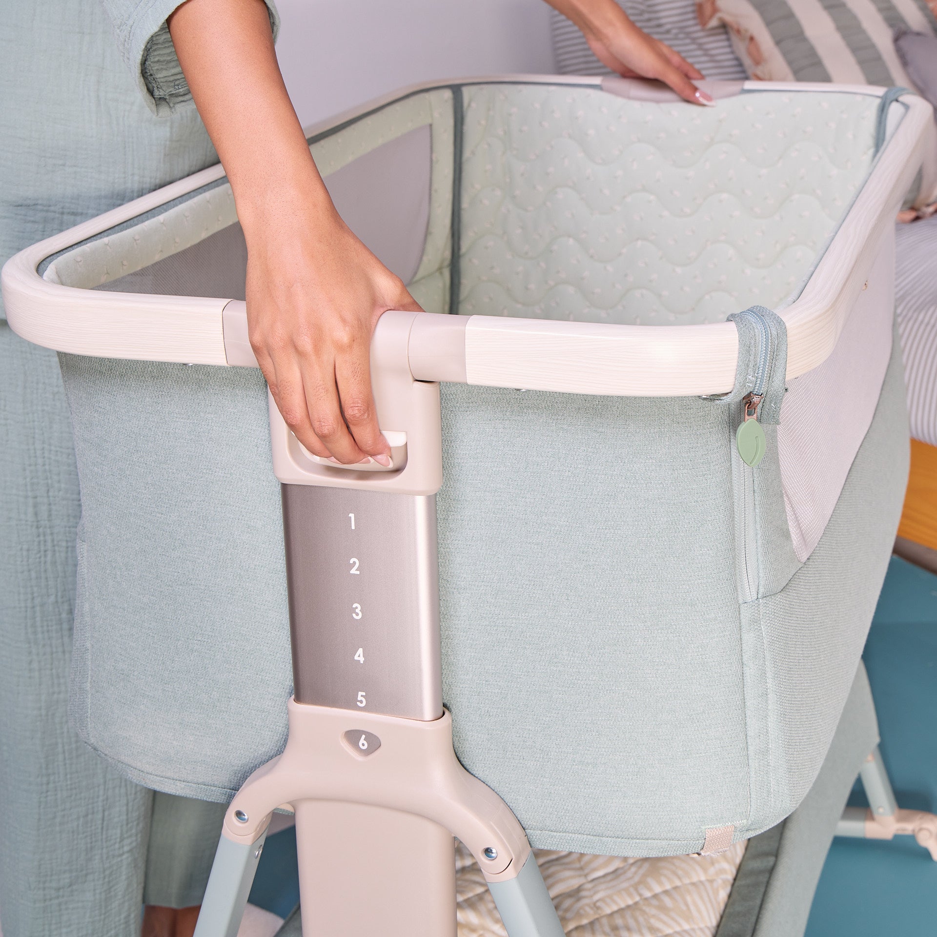Side view of the CoZee Air 2 bedside crib in kelp and whitewash showing numbered height adjustment settings for bedside alignment.