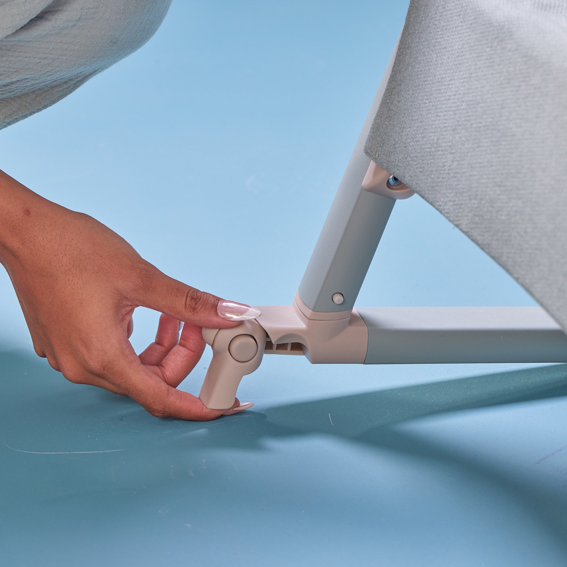 Close-up of the CoZee Air 2 bedside crib in kelp and whitewash showing the foot brake for stable, secure positioning.