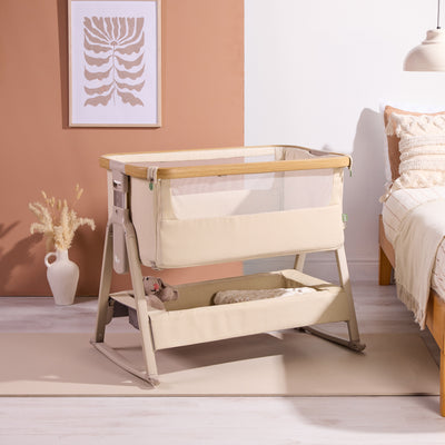 Styled nursery scene featuring the CoZee Air 2 bedside crib in toasted oak/sand with soft textiles and calm, neutral tones.