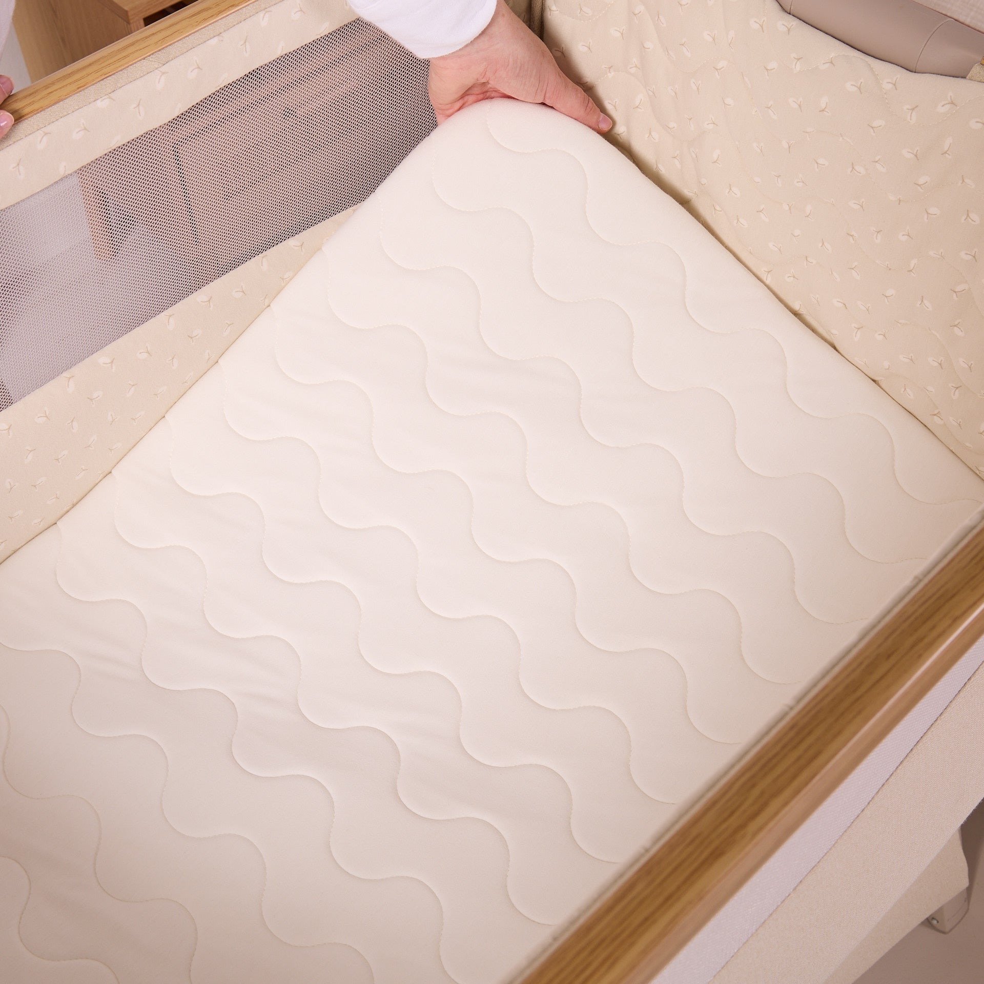 Top view of the CoZee Air 2 bedside crib in toasted oak/sand showing the breathable mattress fitting neatly within the padded sleep space.