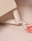 Close-up of the CoZee Air 2 bedside crib in toasted oak/sand showing the foot brake, allowing secure positioning beside the bed.