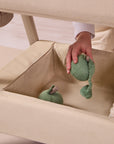 Close-up of the CoZee Air 2 bedside crib in toasted oak/sand showing the integrated storage basket for keeping essentials close.