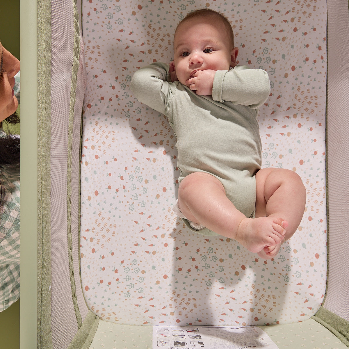 Overhead view of a baby resting comfortably inside the CoZee Zen bedside crib, highlighting the breathable mattress and soft interior fabrics.