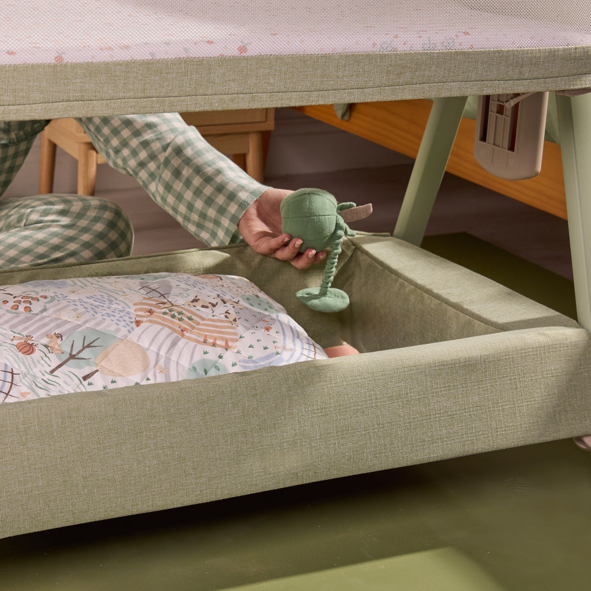 Lifestyle image showing the under-crib storage shelf of the CoZee Zen, with bedding and essentials neatly stored within easy reach.
