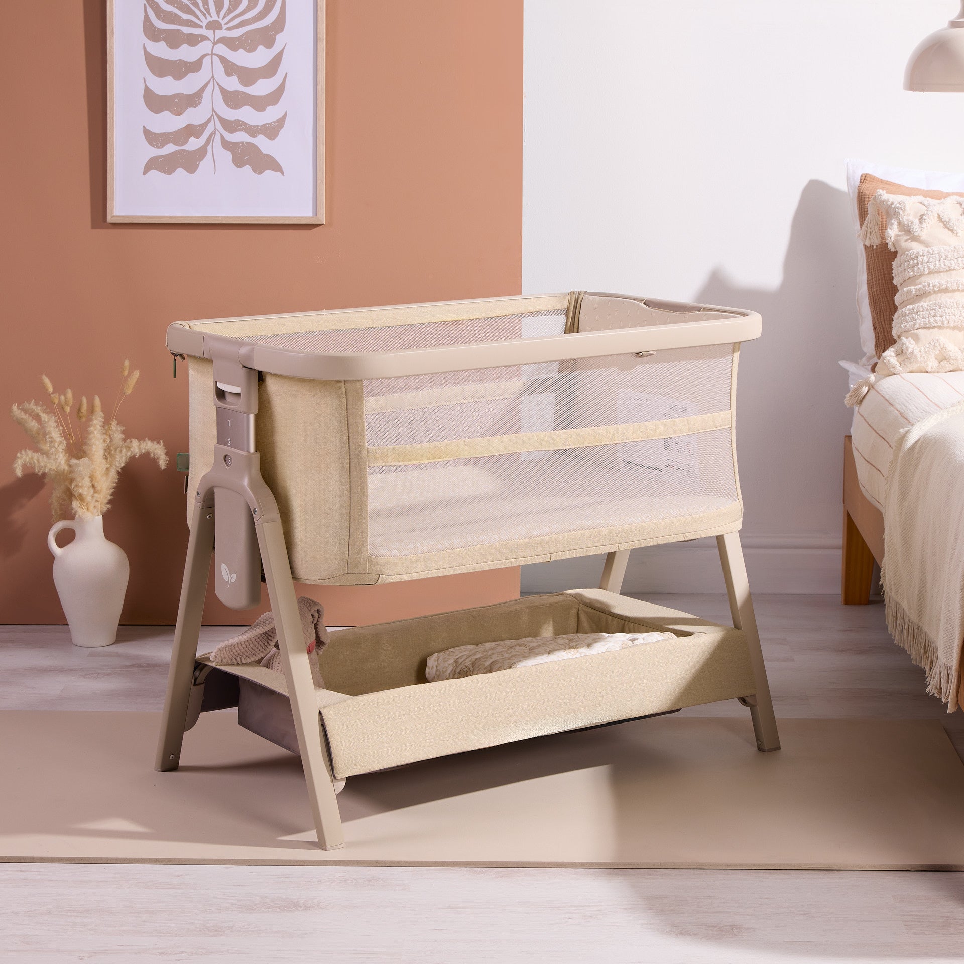 CoZee Zen bedside crib in sand with breathable mesh sides and under-crib storage shelf, styled in a calm neutral bedroom.