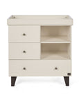 A front view of the Como chest changer in cashmere with a removable changing top, three drawers and open shelving for organised nursery storage.