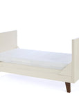 A side view of the Como toddler bed in cashmere and rich walnut, designed with low sides and a modern frame for growing children
