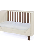 An angle view of the Como sofa bed in cashmere and rich walnut, featuring open sides and slatted back for a stylish and versatile nursery option.