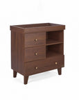 A side view of the Como chest changer in walnut with a removable changing top, three drawers and open shelving for organised nursery storage.