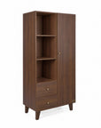 A tall wooden nursery wardrobe at a side angle, with a dark brown walnut finish, featuring three open shelves, one closed door with a small round knob, two drawers at the bottom with matching knobs, and tapered legs, shown on a white background.