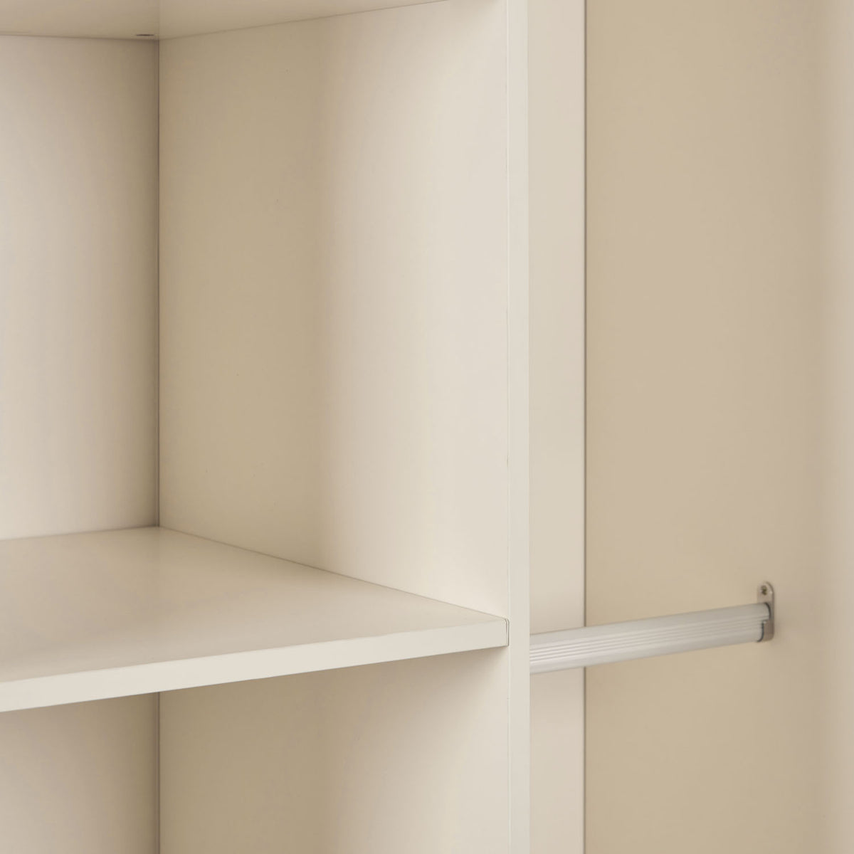 A close up view inside a nursery wardrobe featuring a shelf and metal hanging rail.