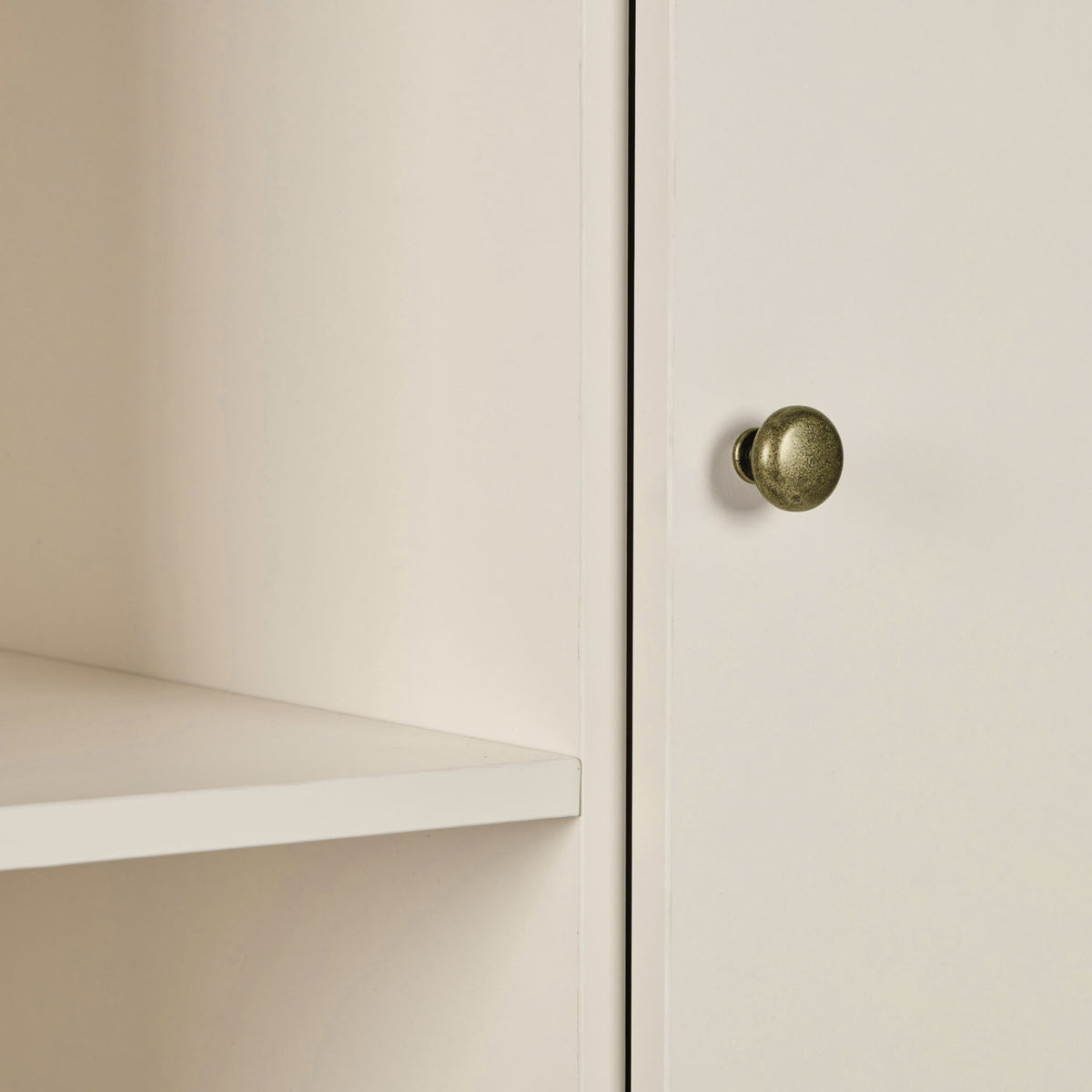 A close up view of a nursery wardrobe featuring a shelf and a round metal wardrobe knob.