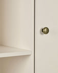 A close up view of a nursery wardrobe featuring a shelf and a round metal wardrobe knob.