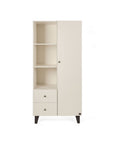 A tall cream-colored nursery wardrobe with a high-shelf design, two drawers underneath, and a single closed door with a small round knob. It stands on short, angled dark legs against a plain white background.