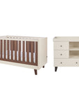 A cot bed and changing table set in cream and dark brown walnut wood, shown on a plain white background.