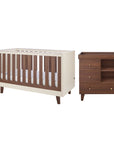 A cot bed and changing table set in cream and matching dark brown walnut wood, shown on a plain white background.