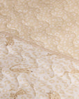 Close-up of the Love Cats cot bed coverlet showing soft quilted texture and reversible beige leopard print design