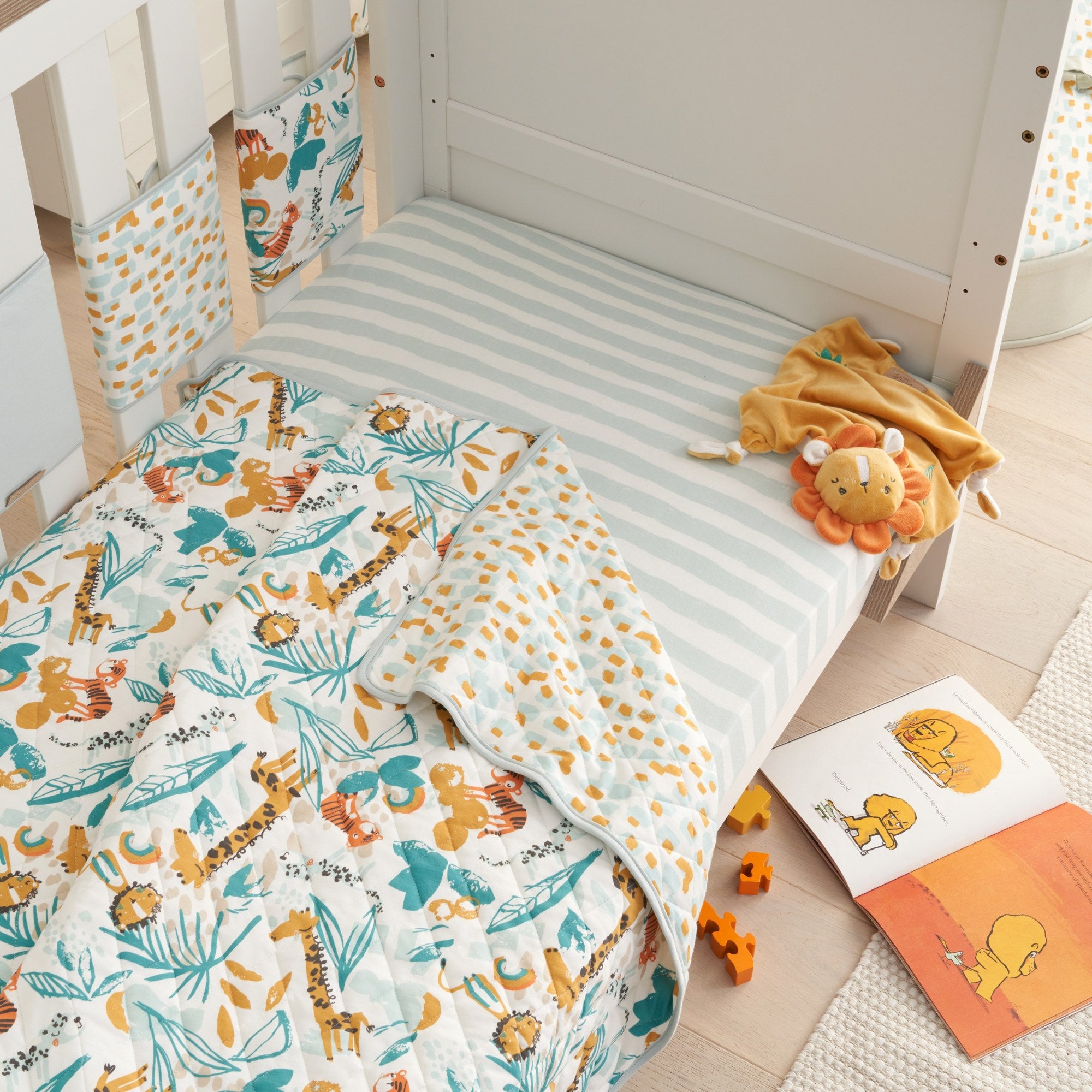 cot bed in sofa bed mode styled with Run Wild cot bed coverlet, showcasing reversible quilted design and animal print for layered comfort.