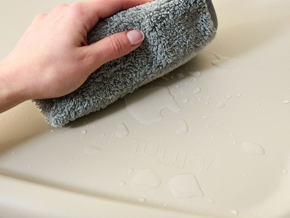 Close-up of the Cushi baby changing mat being wiped clean, highlighting waterproof, easy-care surface